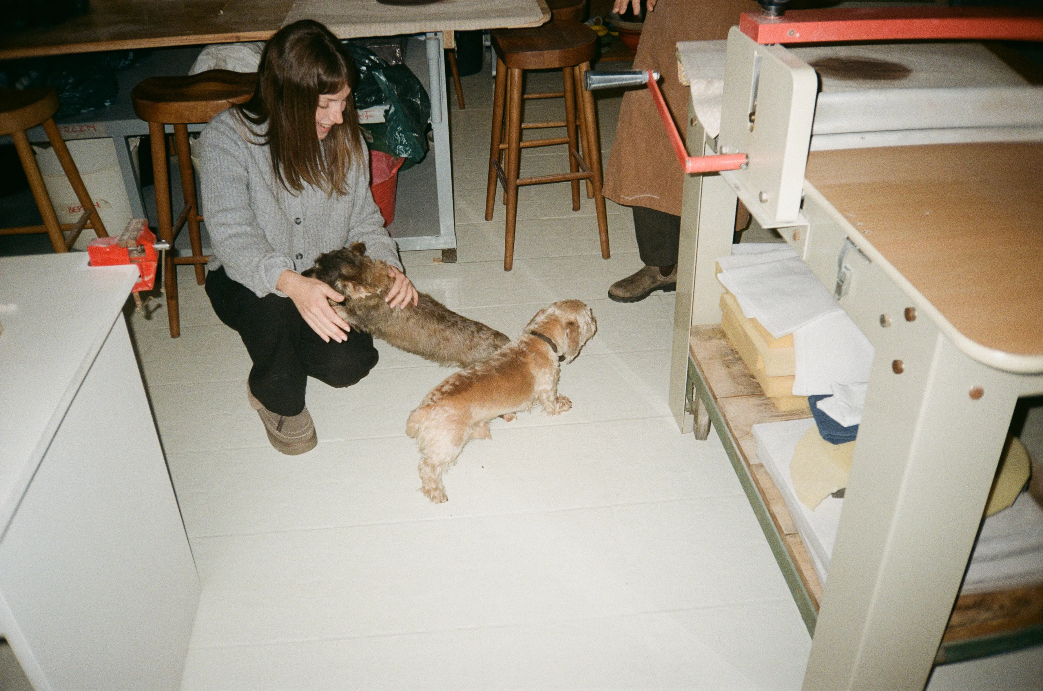 Una alumna saluda a los dos perros del estudio entre las mesas de trabajo