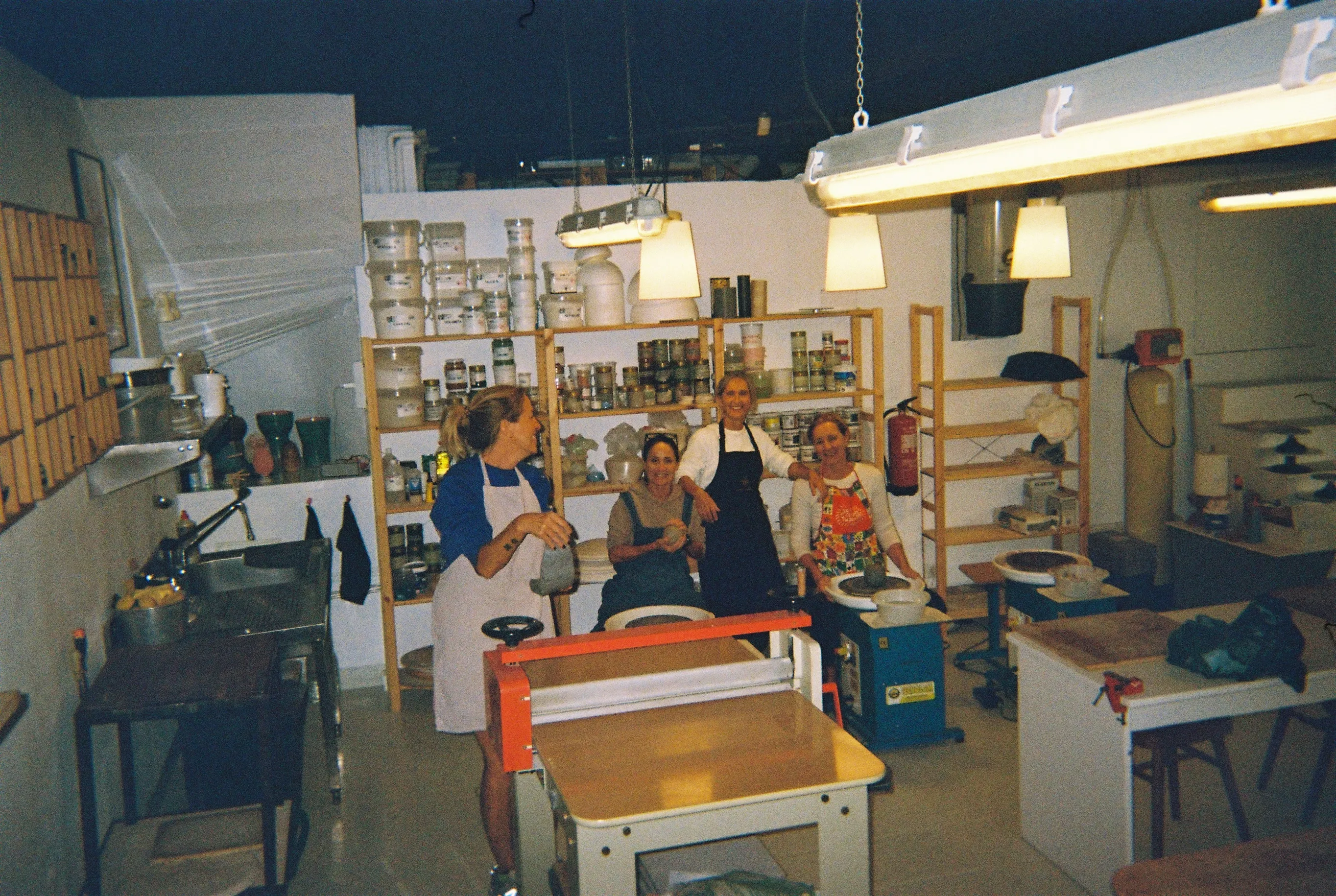 Grupo de alumnas sonriendo entre los tornos y las estanterías de esmaltes durante el taller de Ikebana
