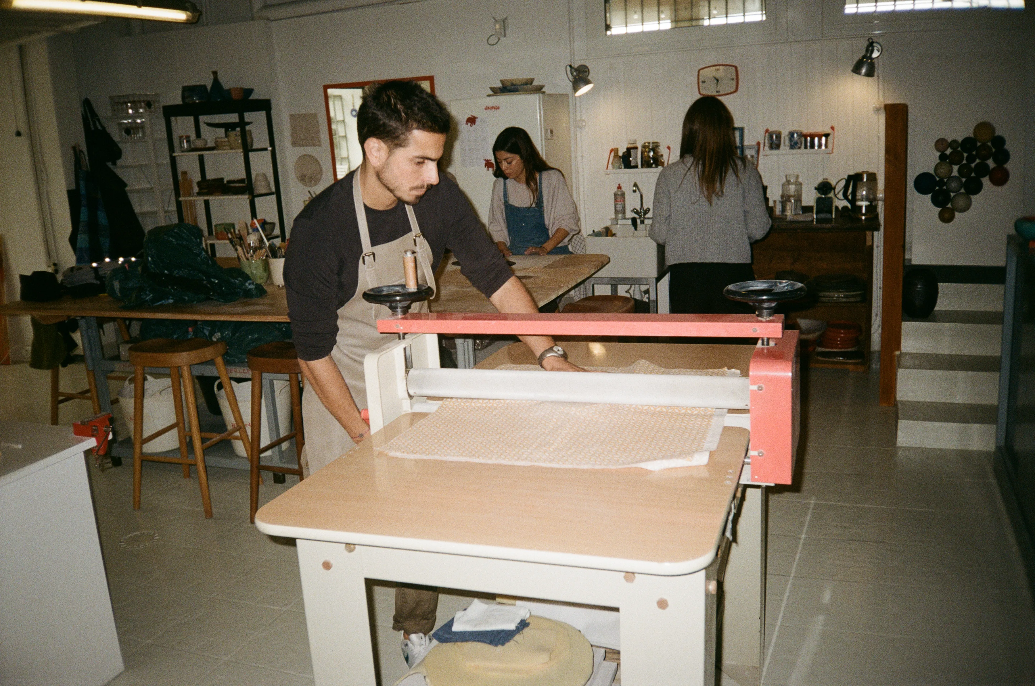 Un alumno extiende una plancha de barro en la laminadora profesional del estudio
