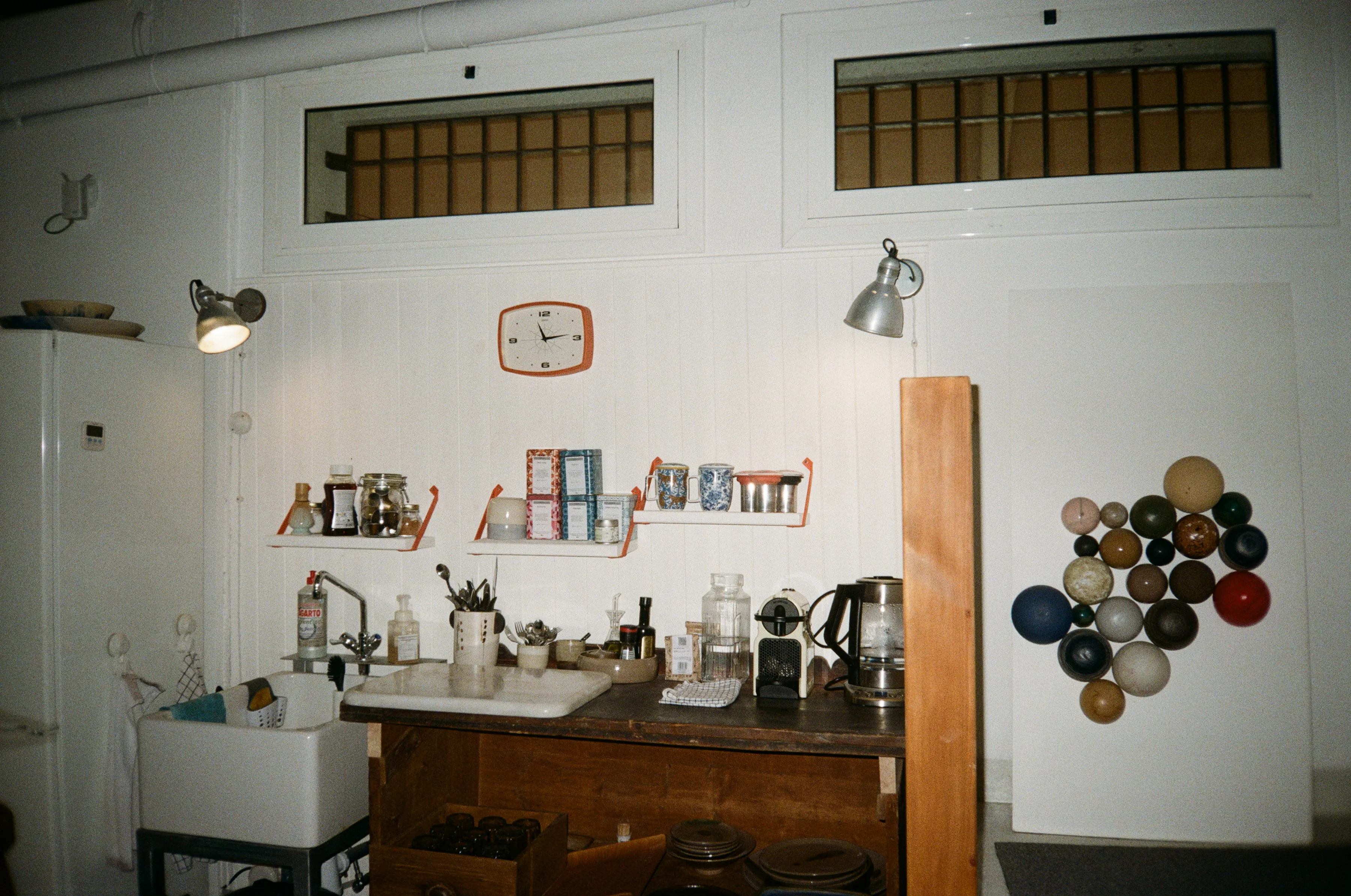 El rincón de té y café del estudio, con la cocina vintage y la pared de esferas de cerámica